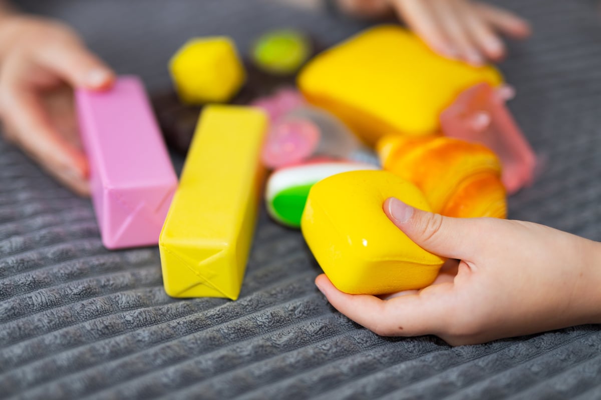 Children's hands holding an assortment of colorful squishy sensory toys